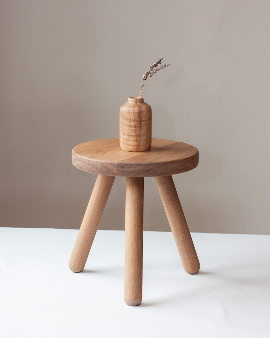 Wooden side table with a vase on a white surface and beige wall background