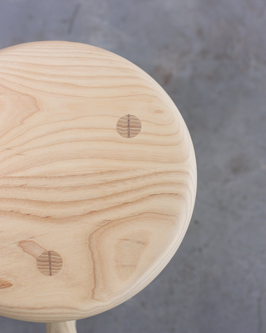 Close-up of a wooden stool with a gray concrete background