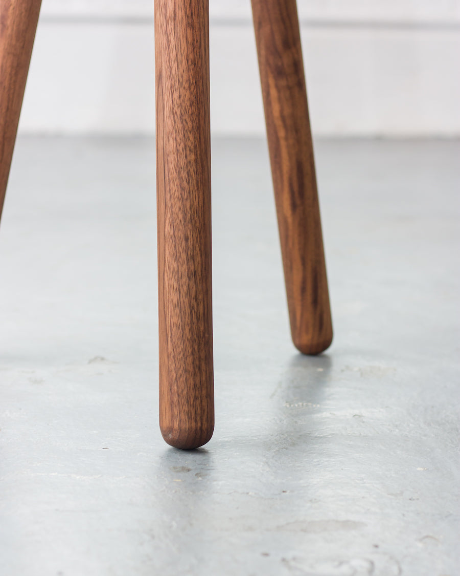 Close-up of three wooden legs on a light gray floor.