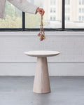 Round wood table with a wooden base in a minimalistic room.
