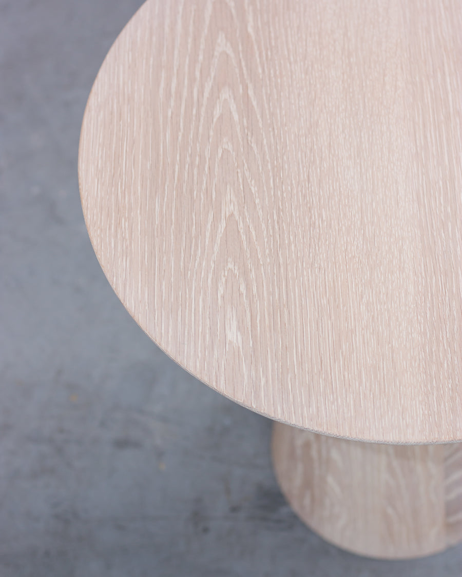 Wooden stool with a light finish on a gray concrete floor