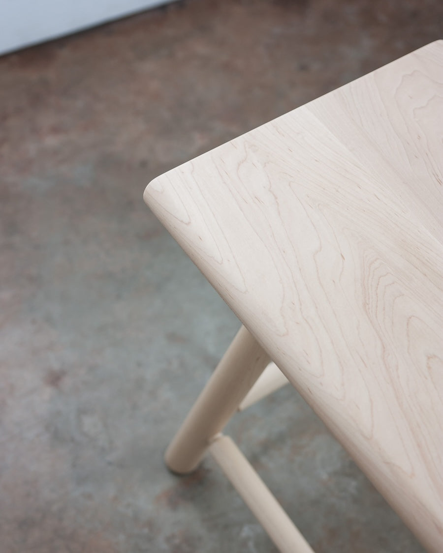 Close-up of a light wooden stool on a concrete floor