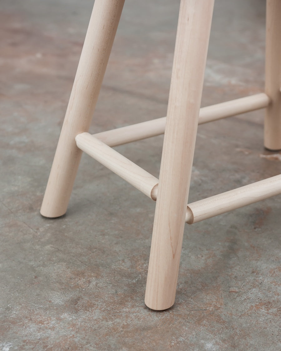 Close-up of wooden stool legs on a concrete floor
