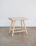 Wooden stool on a concrete floor with a white wall background