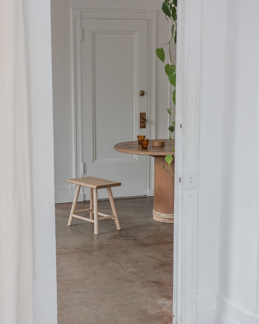 Wooden stool and table in a room with a neutral color scheme