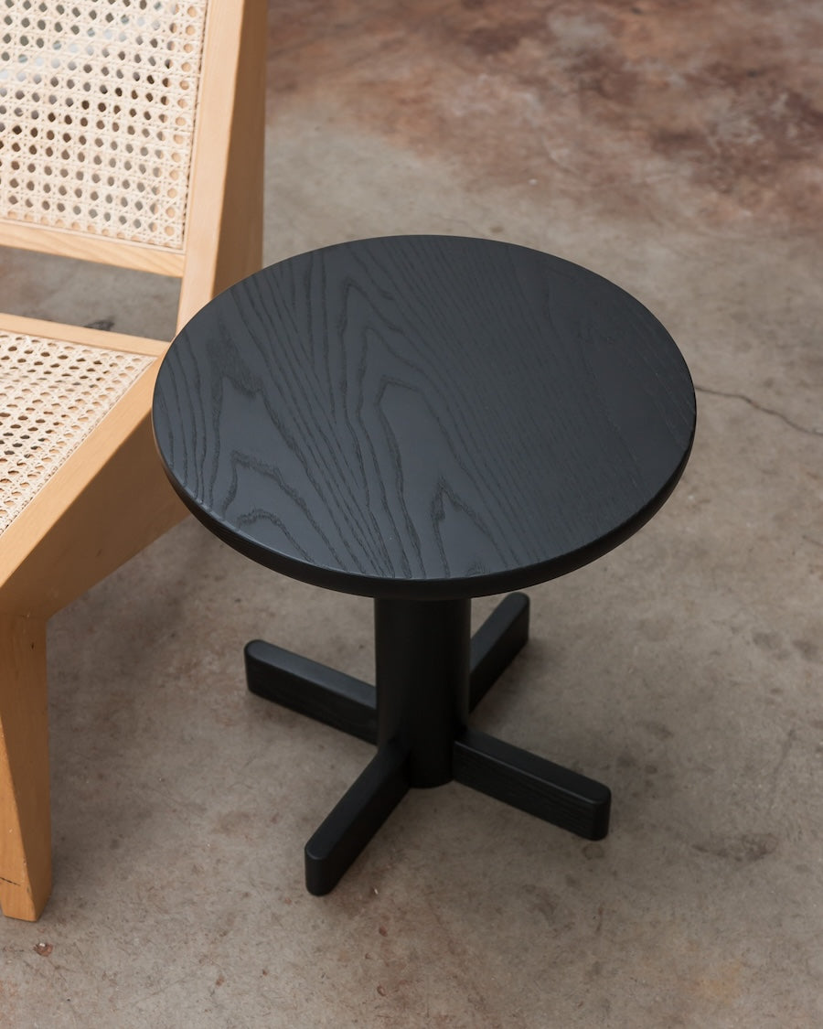 Black round table with a wooden chair on a concrete floor