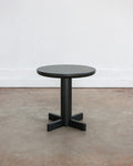 Black round table on a concrete floor with a white wall background