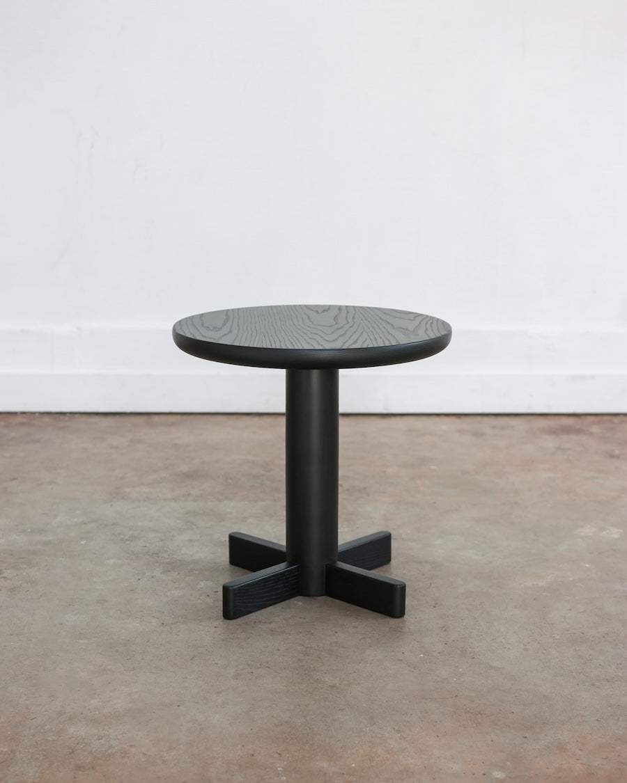 Black round table on a concrete floor with a white wall background