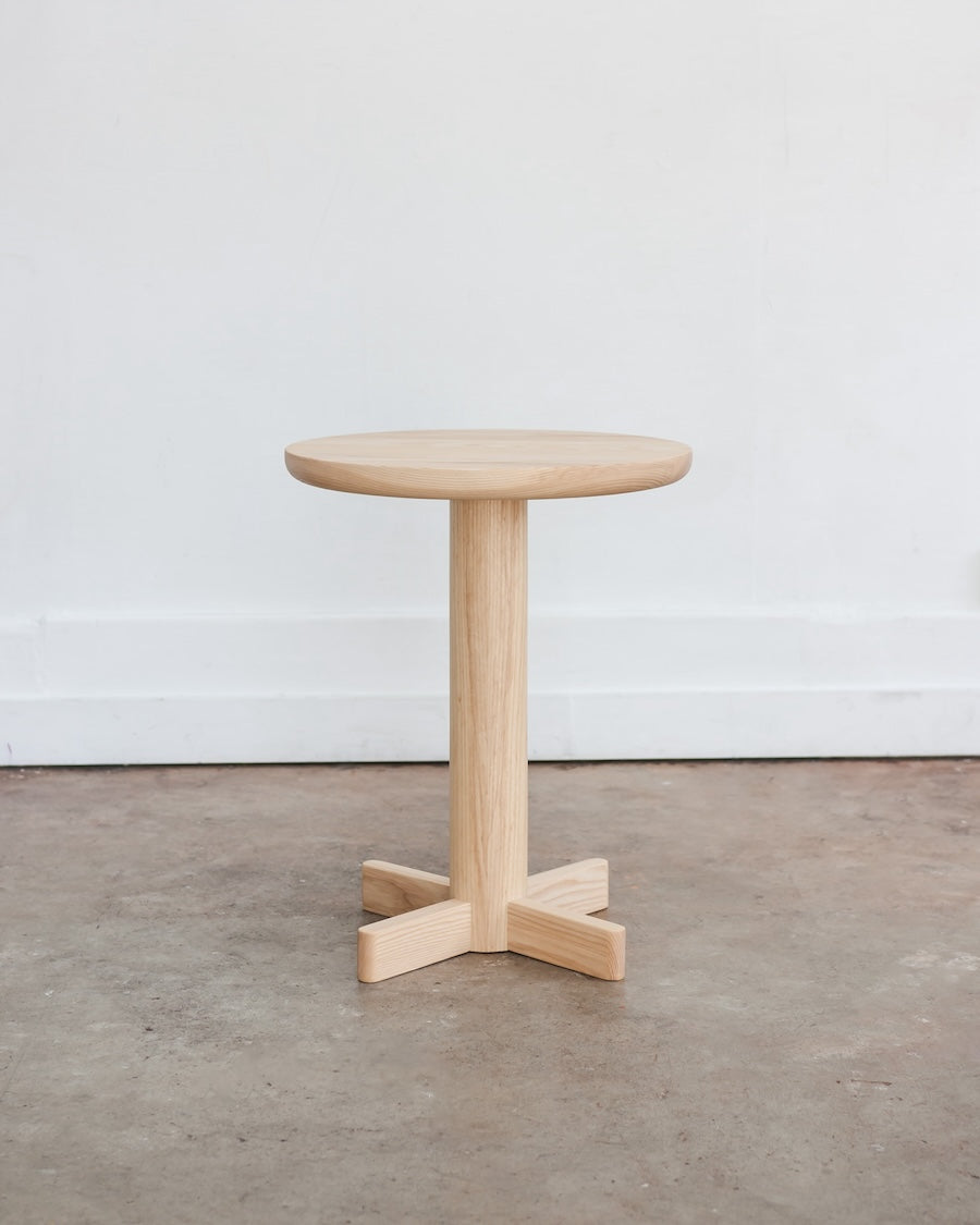 Wooden side table on a concrete floor with a white wall background