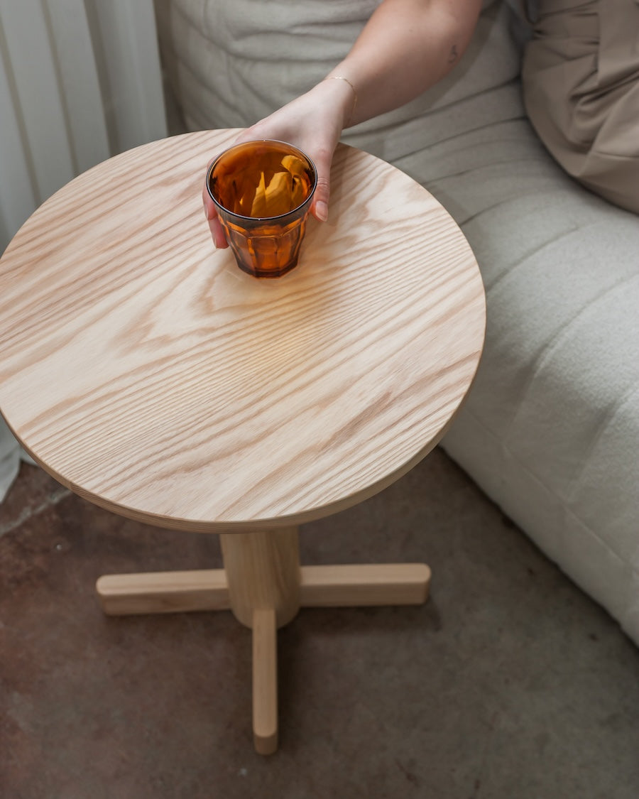 Person holding a glass with snacks on a small wooden table.