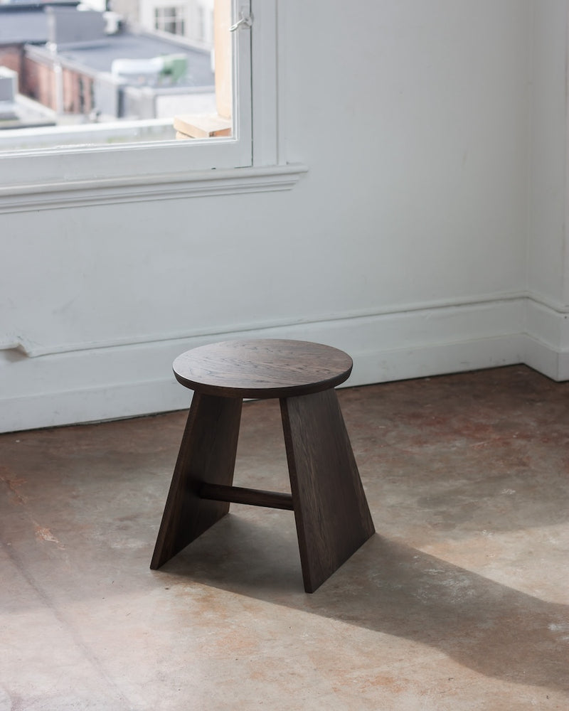 Wooden stool in a room with a window and concrete floor