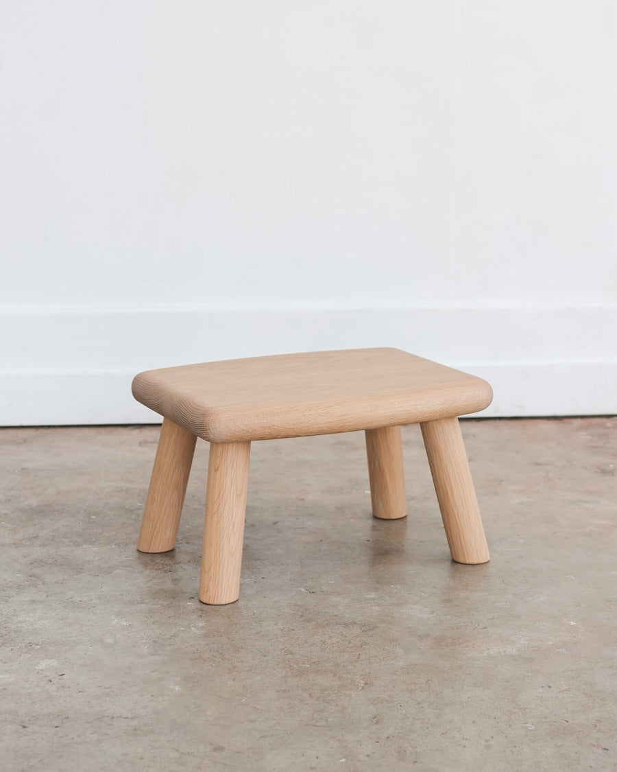 Wooden stool on a concrete floor with a white wall background
