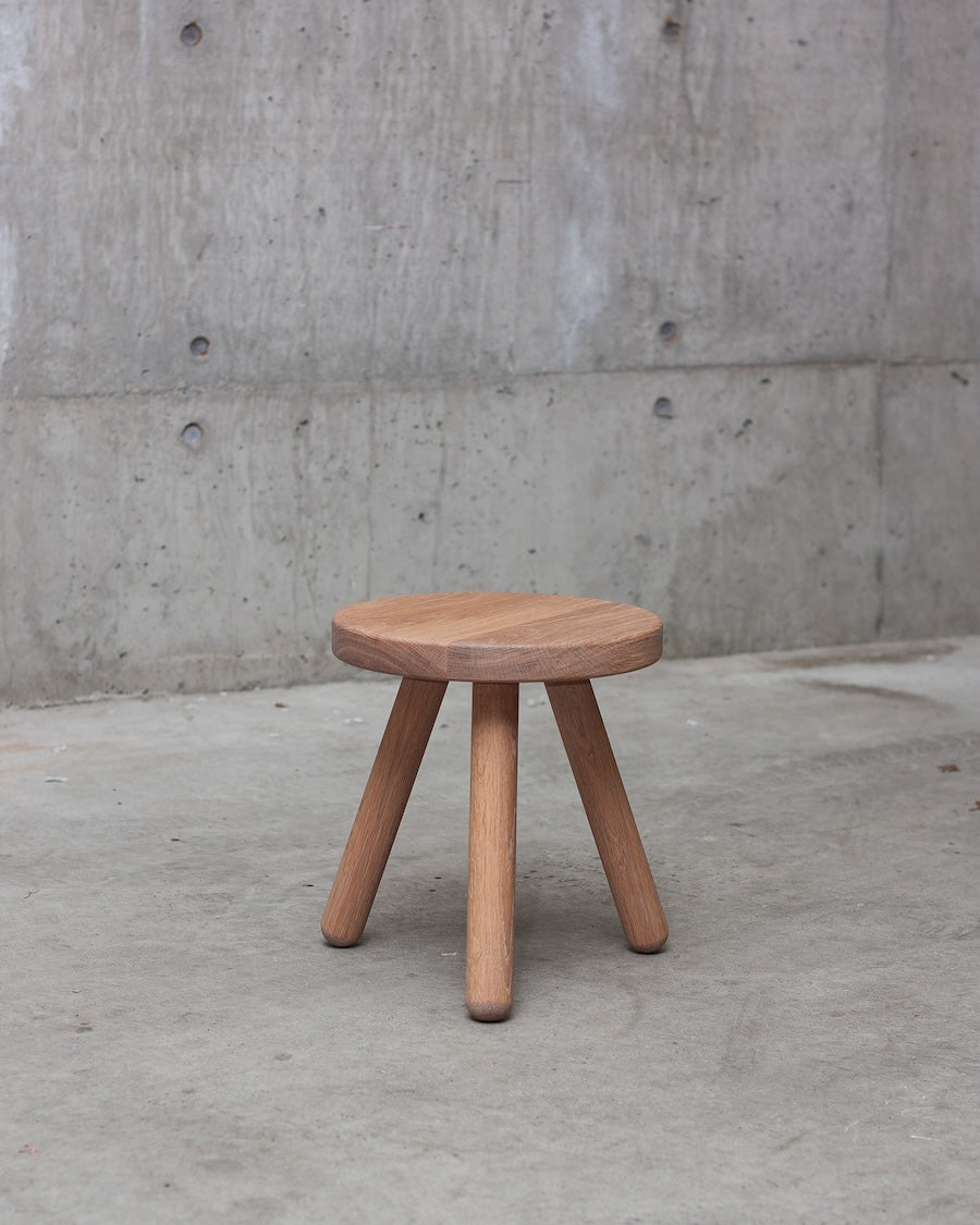 Wooden stool against a concrete wall