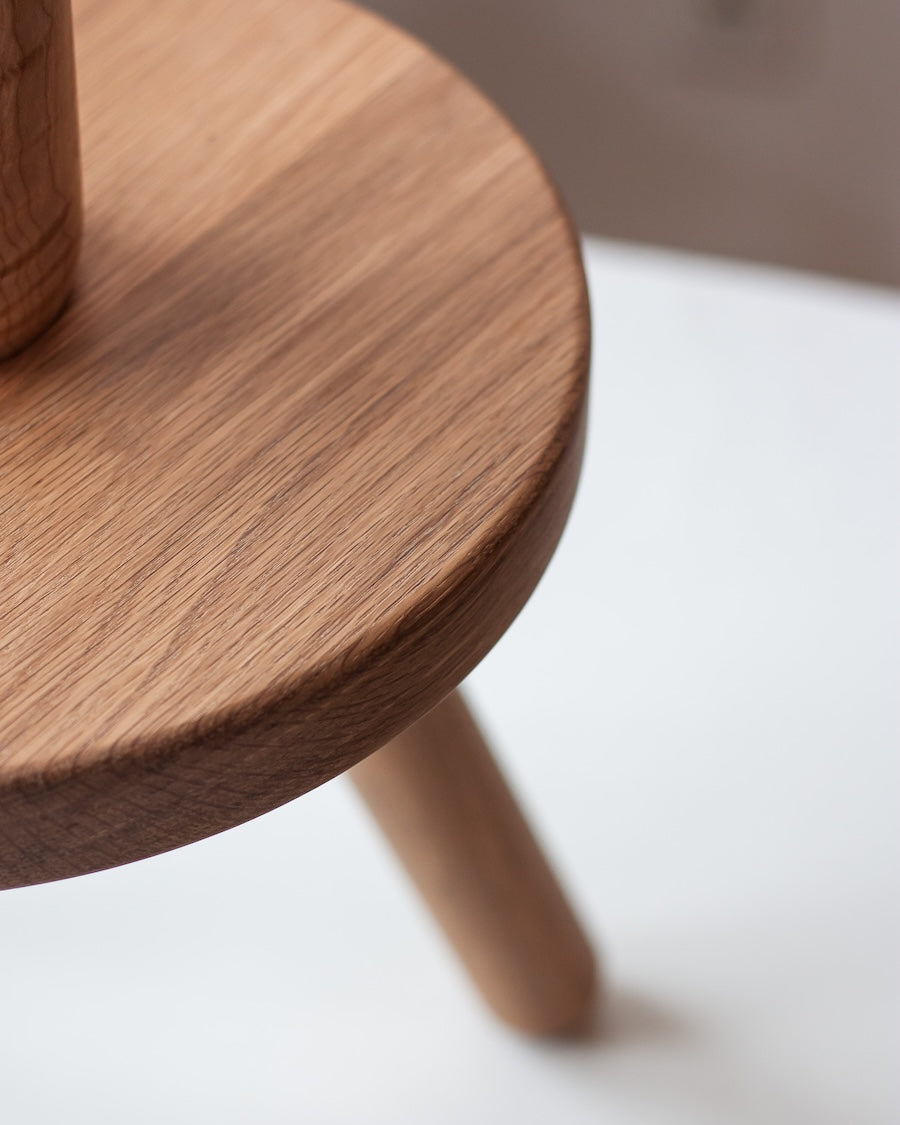 Wooden stool with a round seat and three legs on a white background