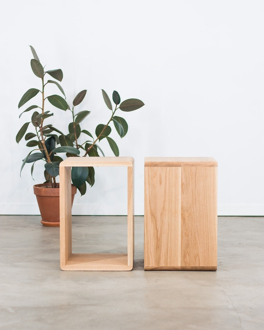 Two wooden side tables with a plant on a light wood floor.