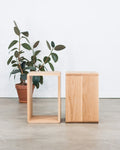 Two wooden side tables with a plant on a light wood floor.