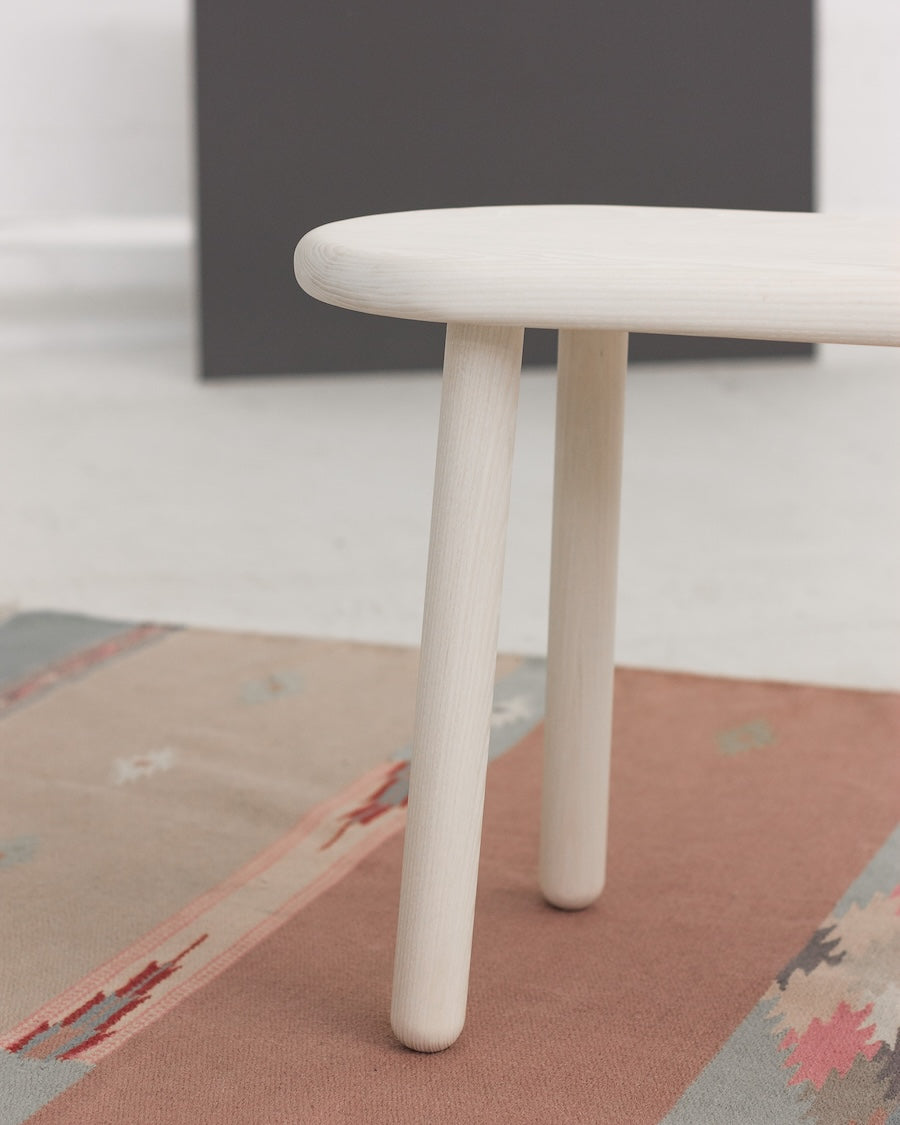 White stool on a patterned rug with a blurred background