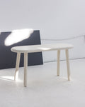 Minimalist white table on a light wooden floor with a white wall background