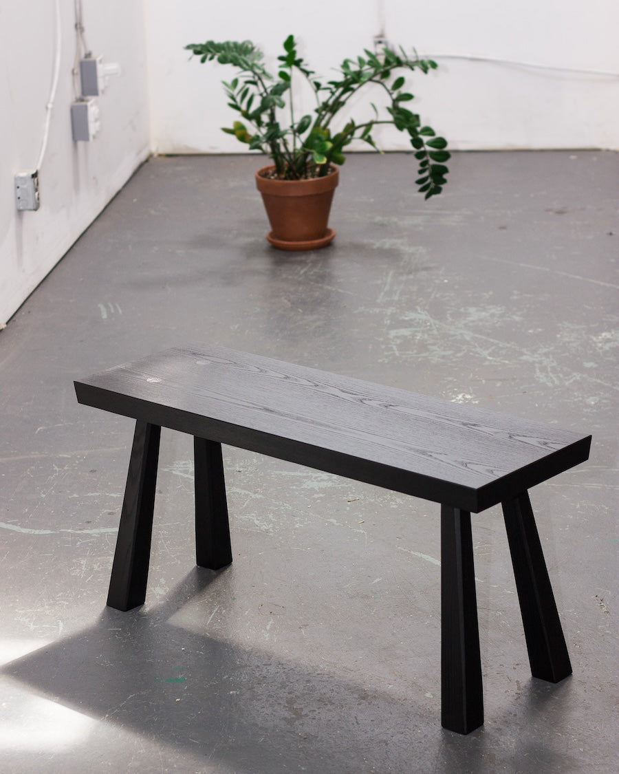 Modern bench with marble-like top and black legs on a concrete floor.