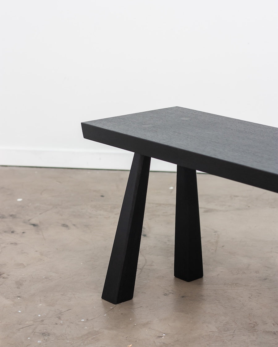 Black stone dining table on a concrete floor with a white wall background