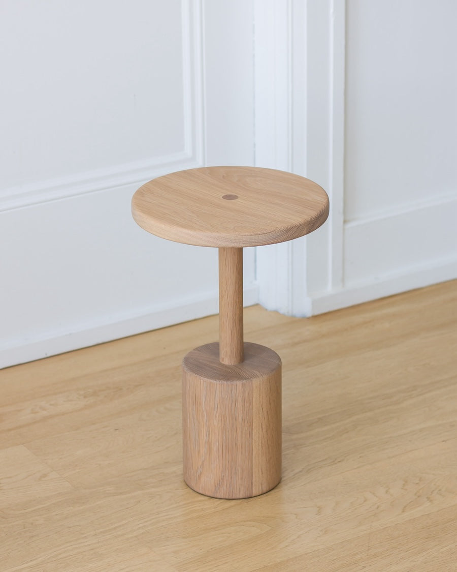 Wooden stool on a wooden floor with a white wall background