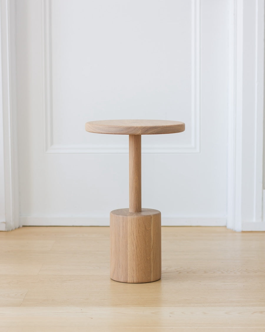 Wooden side table against a white paneled wall