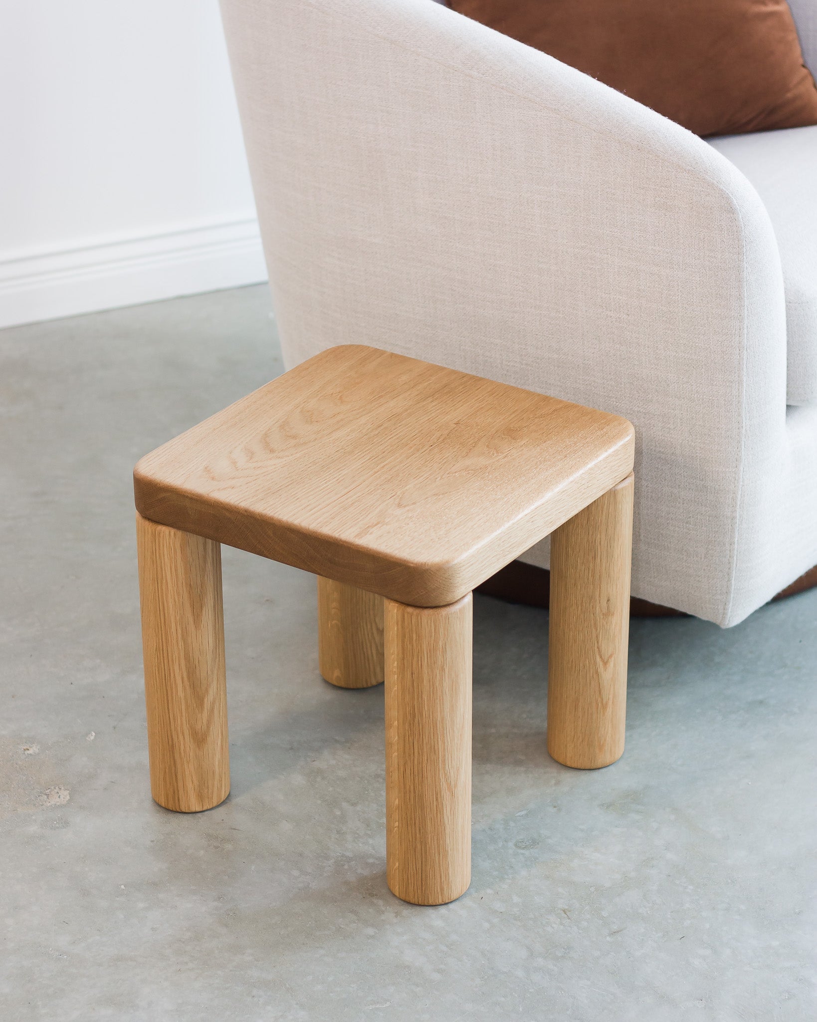 Wooden stool in front of a sofa on a concrete floor