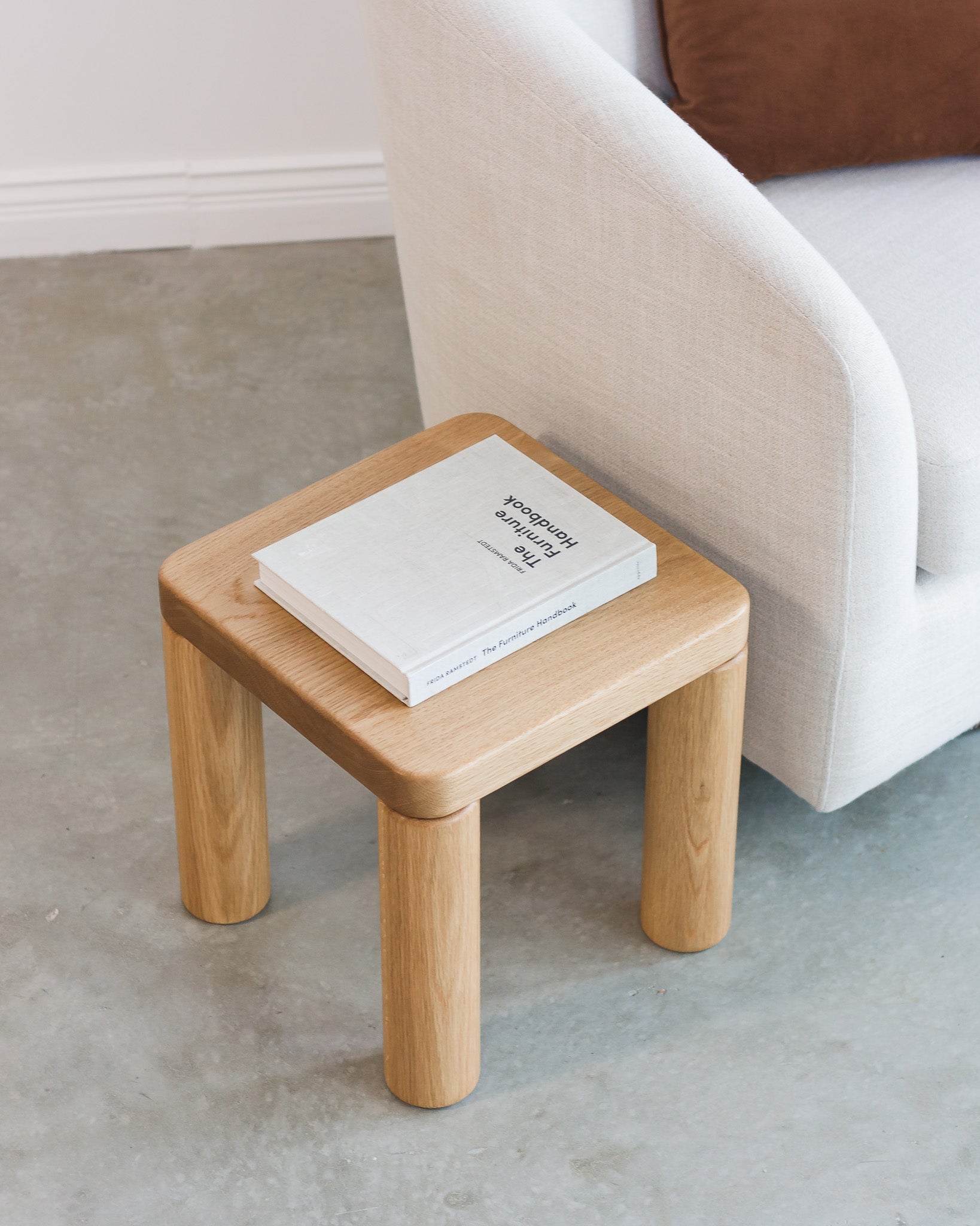 Small wooden side table with a book on it next to a sofa.