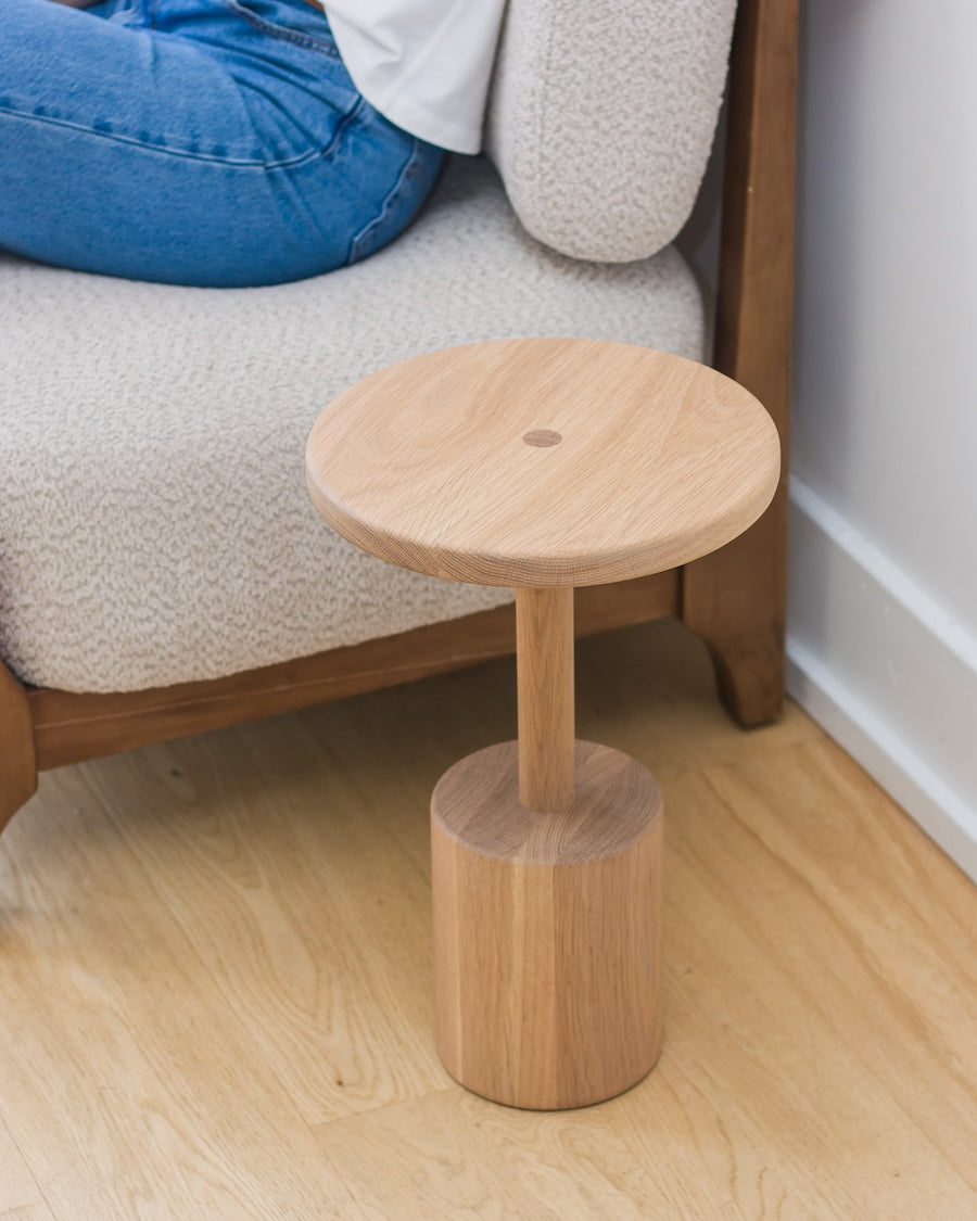 Wooden stool on a wooden floor next to a sofa.